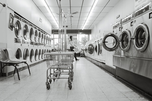 Person standing in a laundromat aisle with washers and dryers on both sides